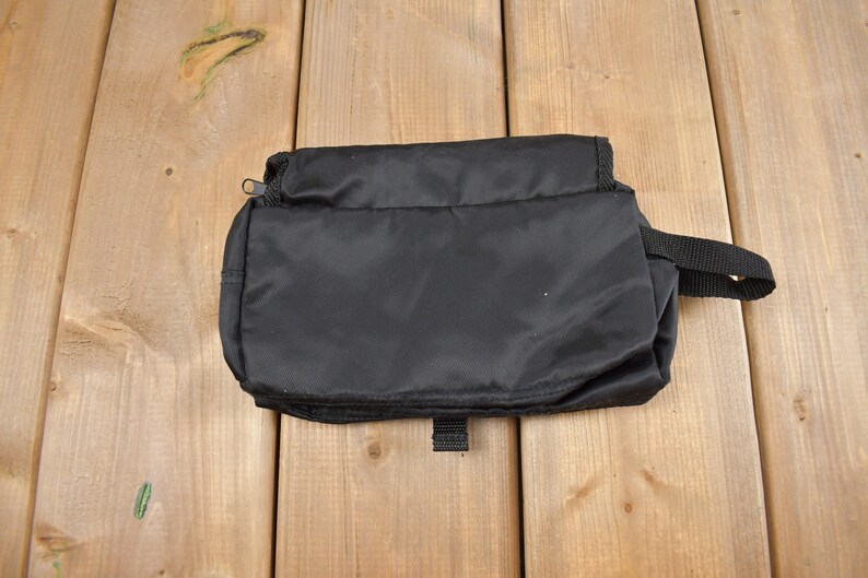 Op de afbeelding: Een zwarte toilettas met rits en een handvat. De tas is gemaakt van waterafstotend nylon.