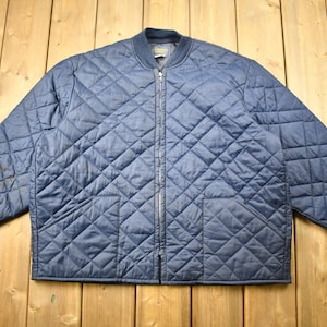 May include: A navy blue quilted jacket with a zipper closure and two pockets. The jacket has a diamond pattern and a ribbed knit collar and cuffs.