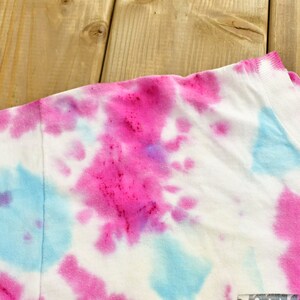 May include: A white t-shirt with a tie-dye pattern in shades of pink and blue.