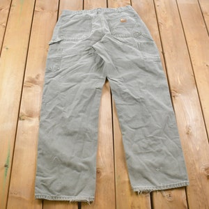 May include: A pair of light grey carpenter jeans with multiple pockets and a worn look.