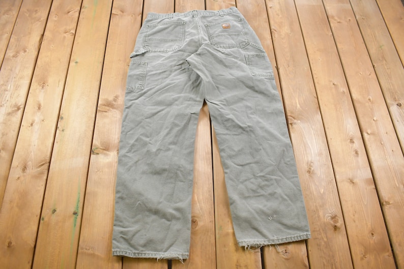 May include: A pair of light grey carpenter jeans with multiple pockets and a worn look.