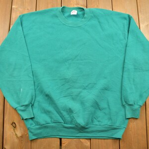 Op de afbeelding: Een turquoise sweatshirt met een ronde hals en lange mouwen.