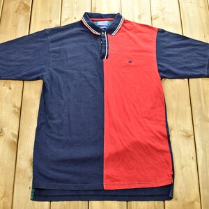 May include: A blue and red polo shirt with a white collar and a small logo on the chest.