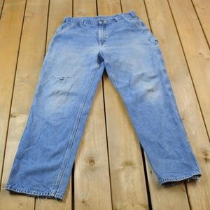 May include: A pair of light blue denim carpenter jeans with a worn look. The jeans have a straight leg and multiple pockets.