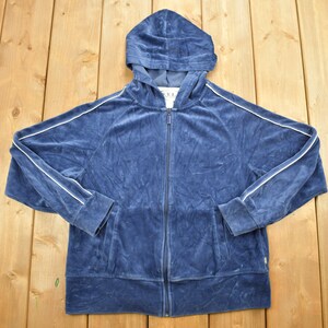 Op de afbeelding: Een blauwe velours zip-up hoodie met witte piping langs de mouwen en de capuchon. De hoodie heeft een capuchon met trekkoord en een voorzak.