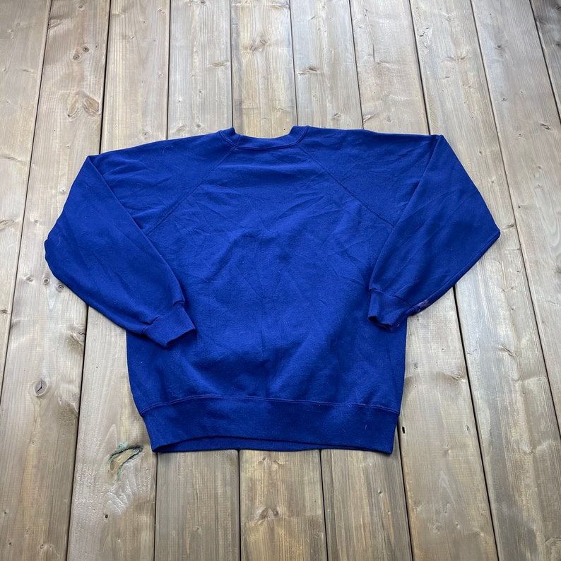 Op de afbeelding: Een donkerblauwe trui met een ronde hals en lange mouwen.