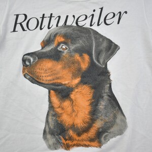 May include: White t-shirt with a black and brown Rottweiler dog illustration and the word "Rottweiler" printed in black.