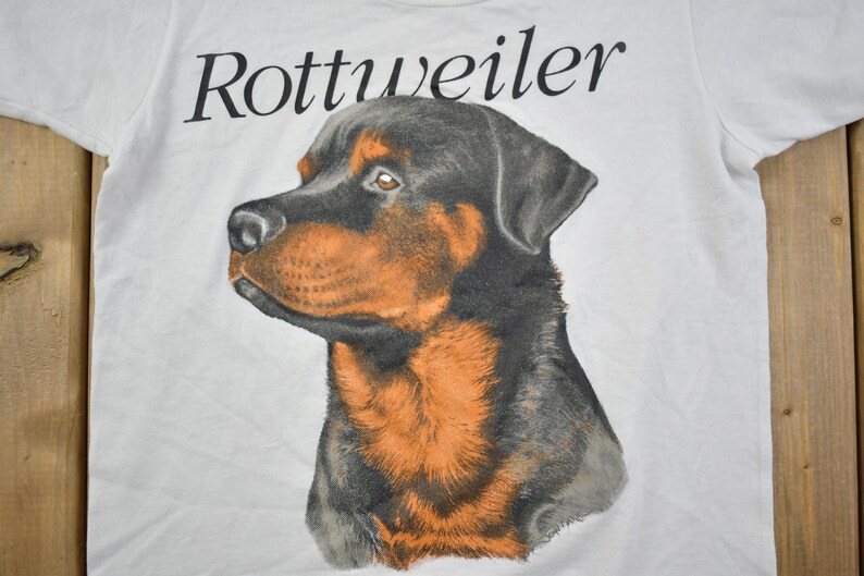 May include: White t-shirt with a black and brown Rottweiler dog illustration and the word "Rottweiler" printed in black.