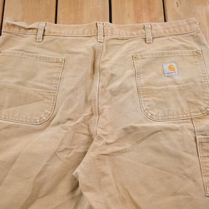 Puede incluir: Un pantal&oacute;n de trabajo de color beige con varios bolsillos, incluido un bolsillo grande en la pierna derecha con un parche de logotipo de Carhartt.