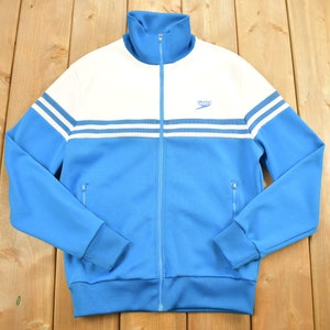 May include: A blue and white track jacket with a white zip and a white stripe down each sleeve. The jacket has a white "Speedo" logo on the chest.