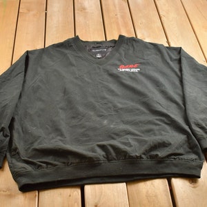 Puede incluir: Chaqueta cortavientos negra con un logotipo rojo "Race" y el texto "The Fastest Show on Earth".