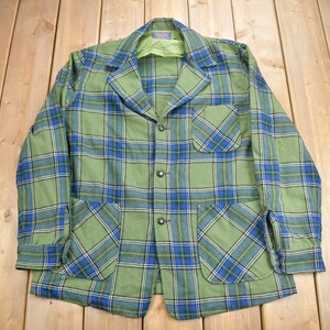 May include: A green, blue, and white plaid jacket with a button-up front and two large pockets.