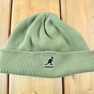 May include: A green knitted beanie with a black kangaroo logo and the word "Kangol" embroidered on the front.