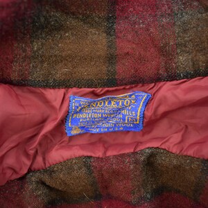 May include: A blue label with white text that reads "The Woolmark, Trade Mark, Pendleton Woolen Mills, Portland, Oregon, 100% Virgin Wool, Made in U.S.A."