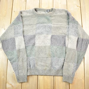 Könnte beinhalten: Ein grauer, grüner und brauner Patchwork-Pullover mit Rundhalsausschnitt.