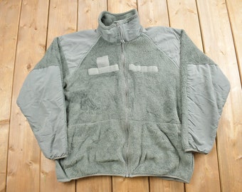 May include: A green fleece jacket with a zipper closure and two pockets. The jacket has a high collar and is made of a soft, warm material.