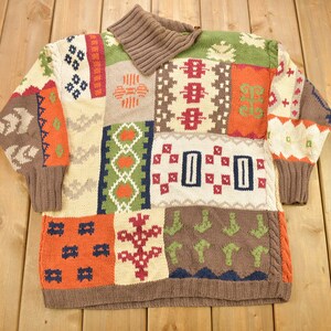 May include: A brown, beige, green, orange and red knitted jumper with a patchwork design and a high collar.