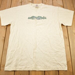 May include: A white t-shirt with a green graphic of a mountain scene and the text "Twin Lakes Trail".