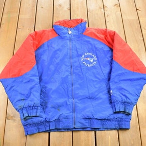 May include: A blue and red jacket with a zipper closure. The jacket has a New England Patriots logo on the front.