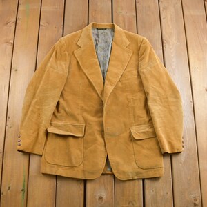 May include: A brown corduroy blazer with a single button fastening and two front pockets.