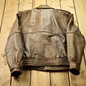 May include: A brown leather bomber jacket with a zipper closure and ribbed cuffs and waistband.