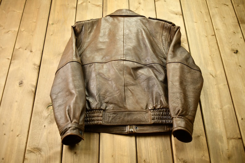 May include: A brown leather bomber jacket with a zipper closure and ribbed cuffs and waistband.