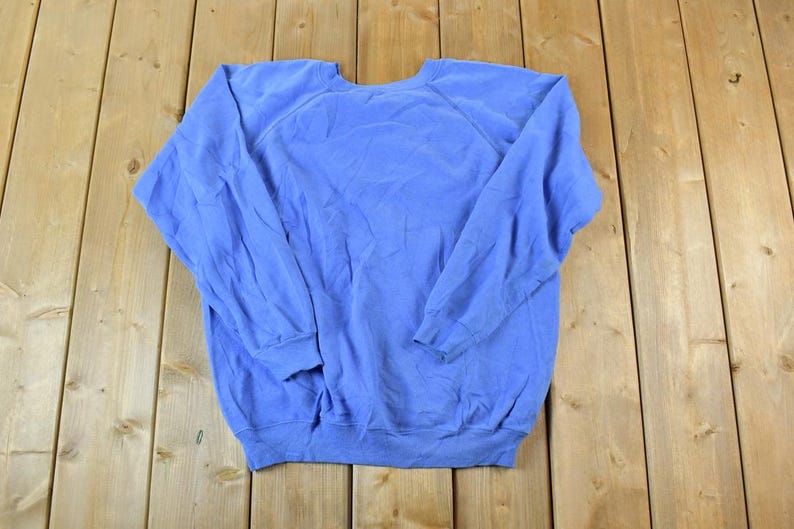 Puede incluir: Una sudadera de color azul claro con mangas largas y cuello redondo.