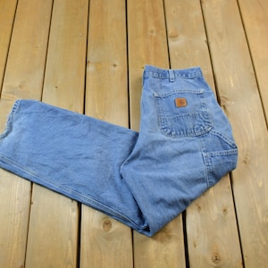 May include: A pair of blue denim carpenter jeans with a brown leather patch on the back pocket.