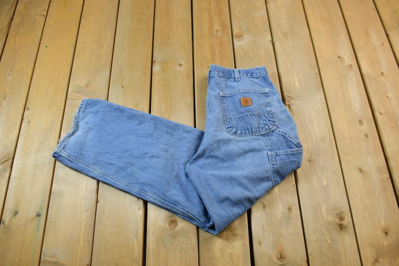 May include: A pair of blue denim carpenter jeans with a brown leather patch on the back pocket.