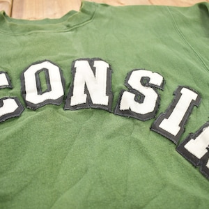 May include: Green sweatshirt with the word "WISCONSIN" in white letters with black outlines.