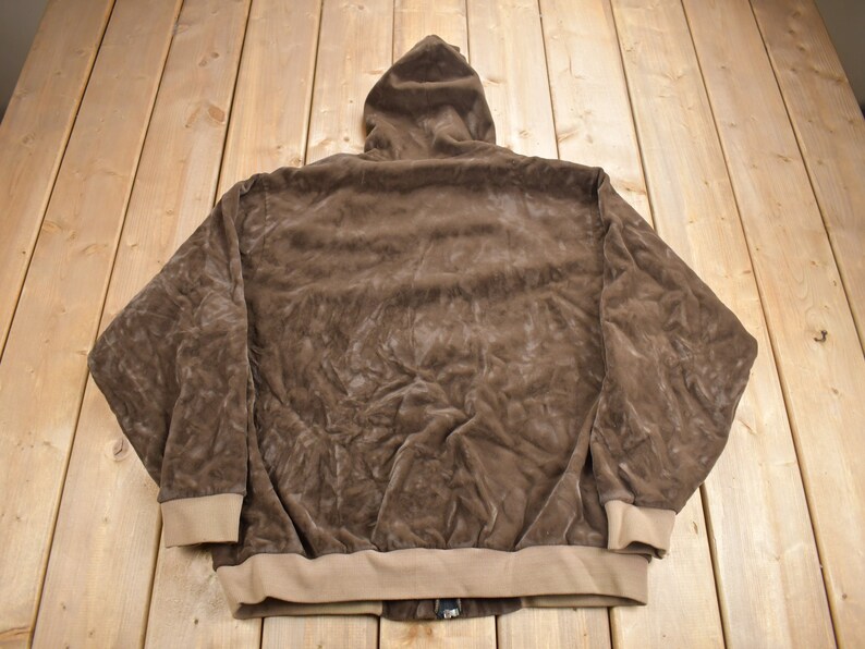 May include: A brown hooded sweatshirt with a zipper closure. The sweatshirt is made of a soft, plush fabric.