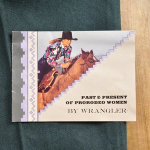 Op de afbeelding: Een vintage pamflet dat Wrangler jeans adverteert met een foto van een vrouw die paardrijdt. De tekst luidt "Past & Present of ProRodeo Women by Wrangler."