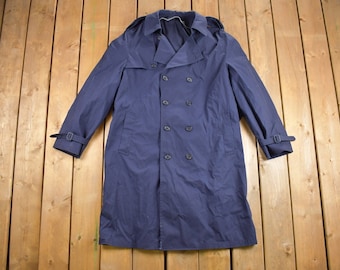 May include: A navy blue double-breasted trench coat with a belt and buttoned cuffs.