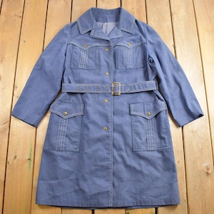 May include: A blue denim coat with a belt, two large pockets, and a button closure.