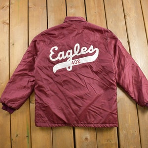May include: A maroon bomber jacket with a white embroidered "Eagles 402" logo on the back.