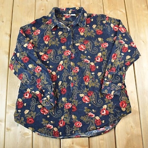 Könnte beinhalten: Langärmliges Hemd in Marineblau mit einem floralen Muster aus roten Rosen, grünen Blättern und Paisley-Designs. Das Hemd hat einen Kragen und geknöpfte Manschetten. Das Material ist weich.