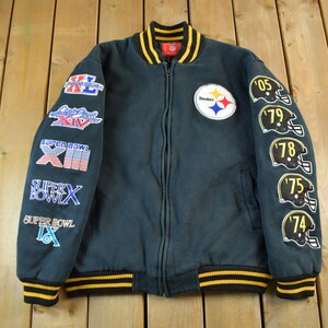 Könnte beinhalten: Dunkelblaue Jacke mit Reißverschluss und gelb-schwarzem Streifenbesatz. Mit dem Logo der Pittsburgh Steelers und Super Bowl-Patches auf den Ärmeln. Enthält Helm-Patches mit den Jahren '05, '79, '78, '75 und '74.