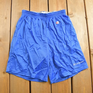 May include: Blue mesh athletic shorts with an elasticated waistband. The shorts feature the Champion logo on the left leg and a Champion logo patch on the left thigh. The shorts are made of a lightweight, breathable material.