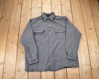 May include: A gray long-sleeved button-up shirt with two chest pockets.