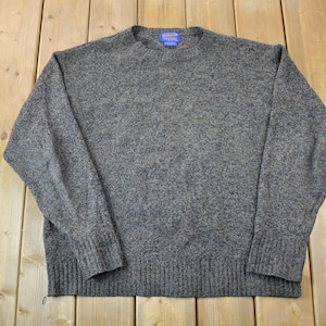 Puede incluir: Un suéter gris jaspeado con cuello redondo y mangas largas. El suéter está hecho de un material suave y cómodo.