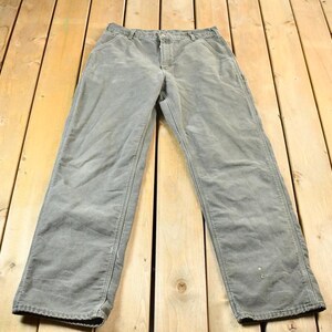 Pu&ograve; includere: Un paio di pantaloni da lavoro grigi a gamba dritta.