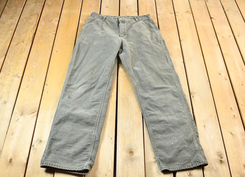 Pu&ograve; includere: Un paio di pantaloni da lavoro grigi a gamba dritta.