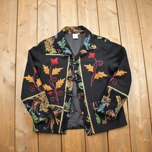 May include: A black jacket with floral embroidery in shades of red, yellow, and green. The jacket has a gold trim and a button closure.