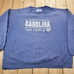 May include: A blue sweatshirt with the text "CAROLINA TAR HEELS" in white lettering.