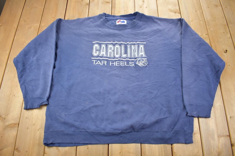 May include: A blue sweatshirt with the text "CAROLINA TAR HEELS" in white lettering.