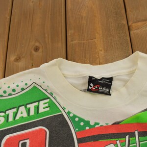 May include: White t-shirt with a green, red and black graphic print featuring the words "Interstate" and "Chase Automotive".