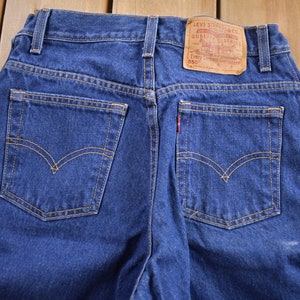 May include: A pair of blue denim jeans with a brown leather Levi's patch on the back pocket. The patch has the text "Levi Strauss & Co. Quality Clothing" and "Every Garment Guaranteed 550".