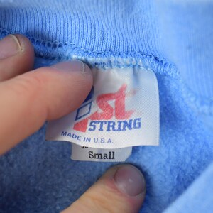 May include: A blue sweatshirt with a white tag that says "1st String Made in U.S.A. Small"