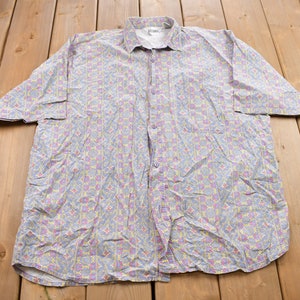 May include: A light blue button-down shirt with a colorful floral pattern. The shirt has short sleeves and a button-up front.