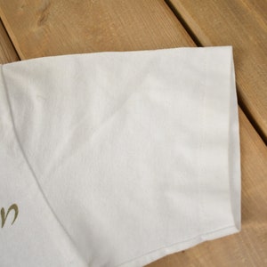 May include: White t-shirt with a gold "Aladdin" graphic on the front.